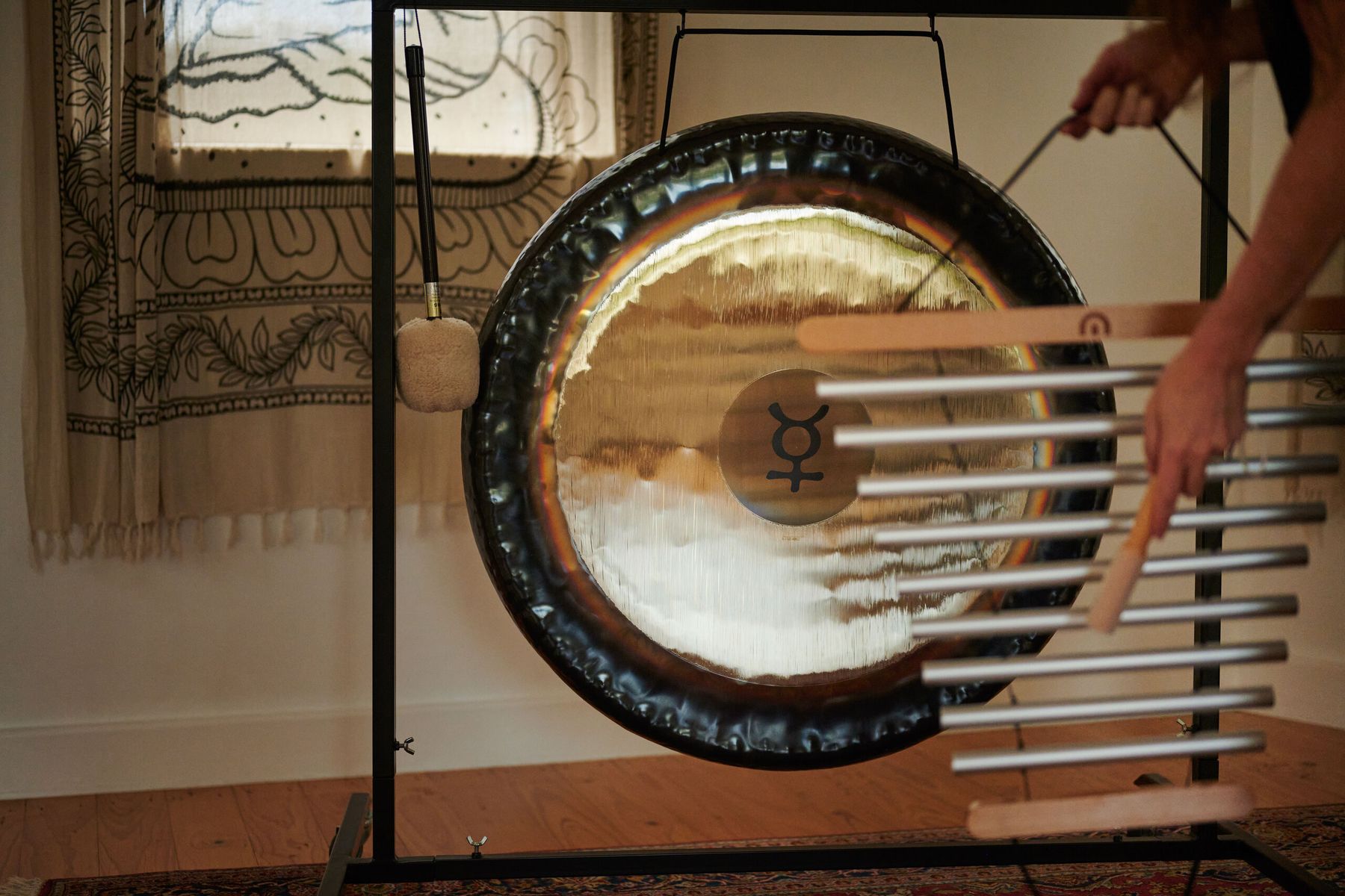 A player runs a chime bar across the face of a planetary gong