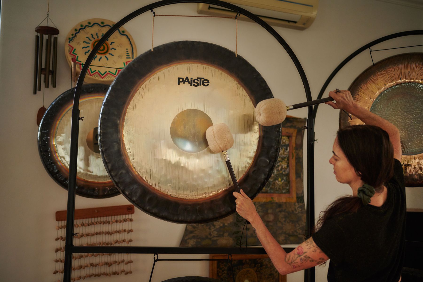 A player strikes a large Paiste gong with two mallets