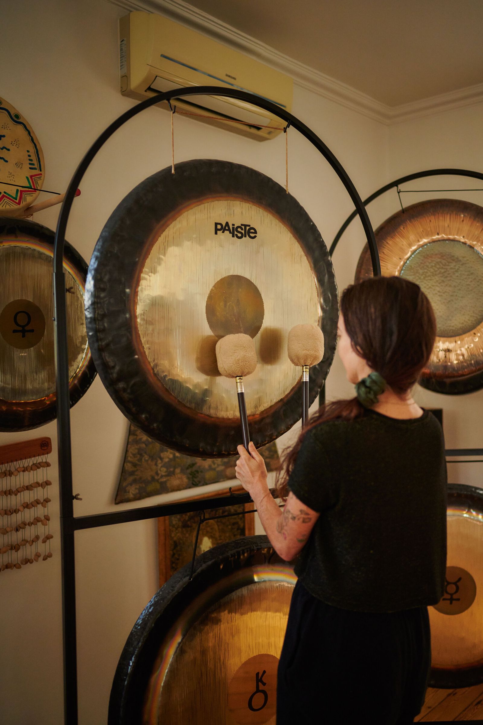 A player reaches up to a large Paiste gong on its stand