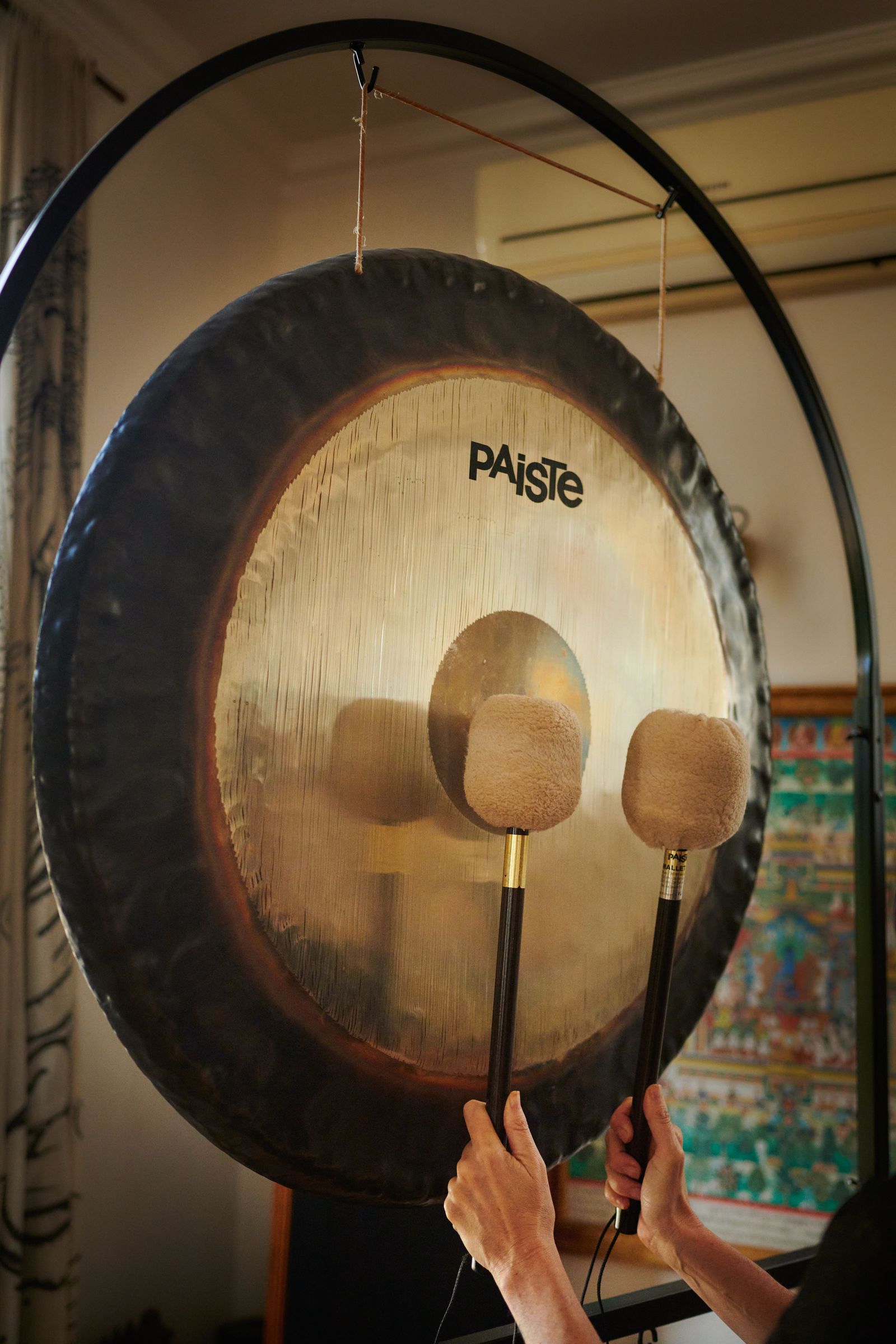 Two felt mallets resting on the face of a large Paiste gong in its stand