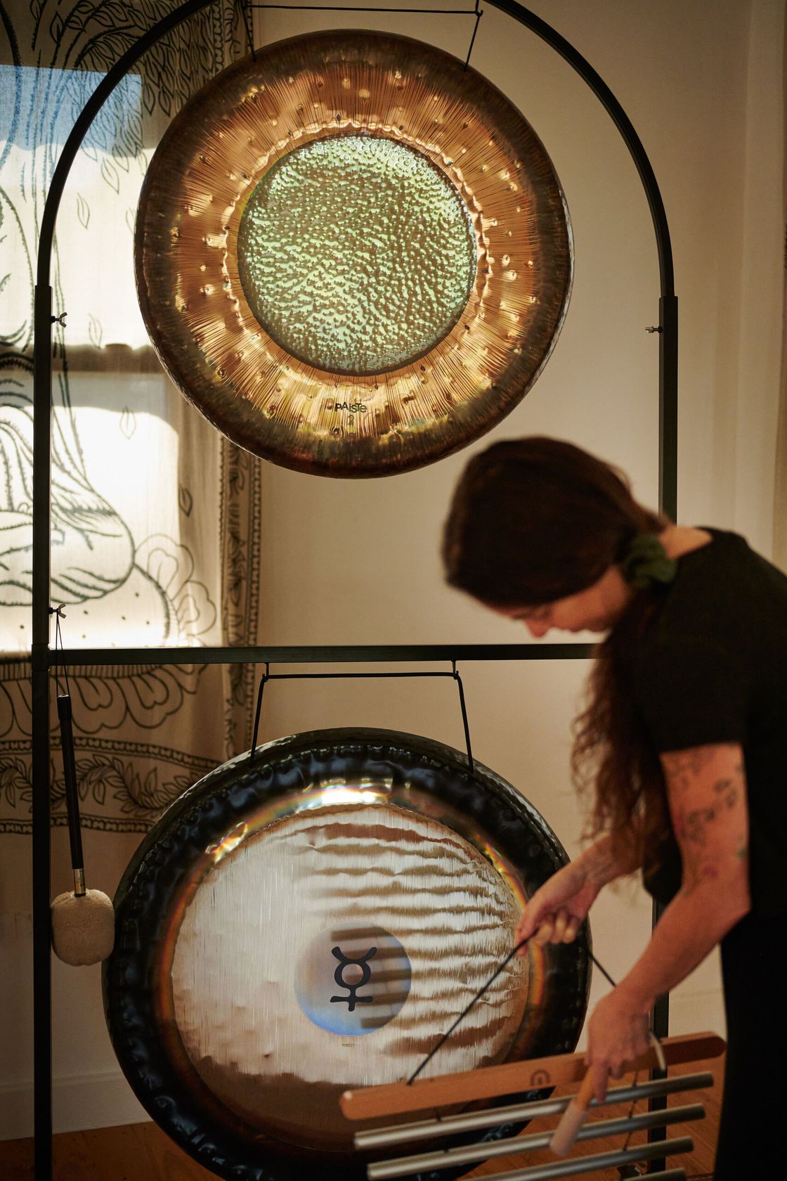 A player plays chimes beneath two hanging gongs