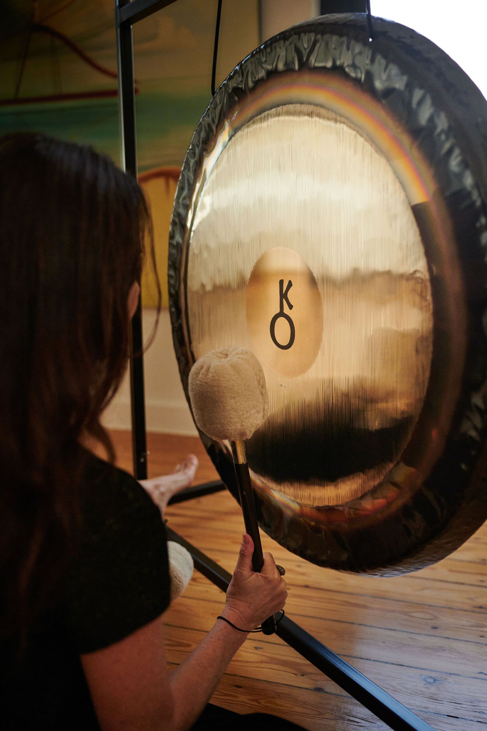 A player strikes a planetary gong with two felt mallets